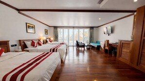 Una habitación de hotel con tres camas, un escritorio, una silla y un televisor.