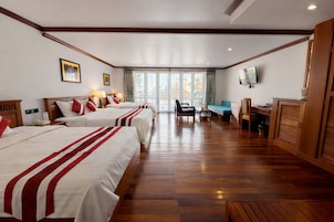 Una habitación de hotel con tres camas, un escritorio, una silla y un televisor.