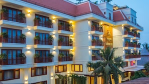 Un hotel de varios pisos con balcones, plantas en macetas e iluminación cálida.