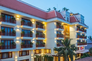 Un hotel de varios pisos con balcones, plantas en macetas e iluminación cálida.