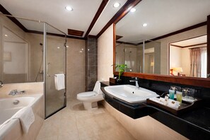 Un baño moderno con ducha de vidrio, inodoro blanco, lavamanos grande y espejo con marco de madera.