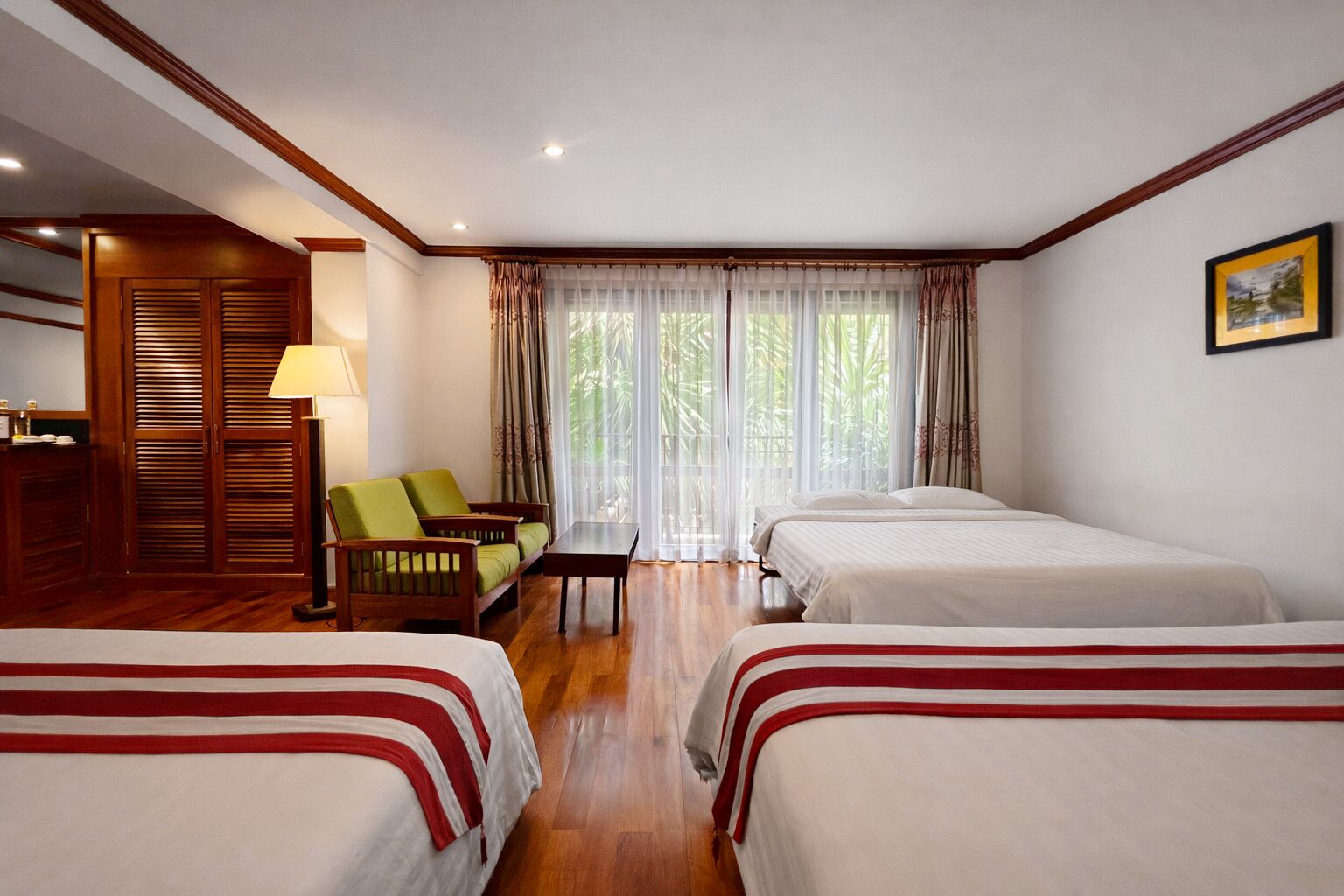 Habitación de hotel con dos camas, un sofá, una mesa y una lámpara.