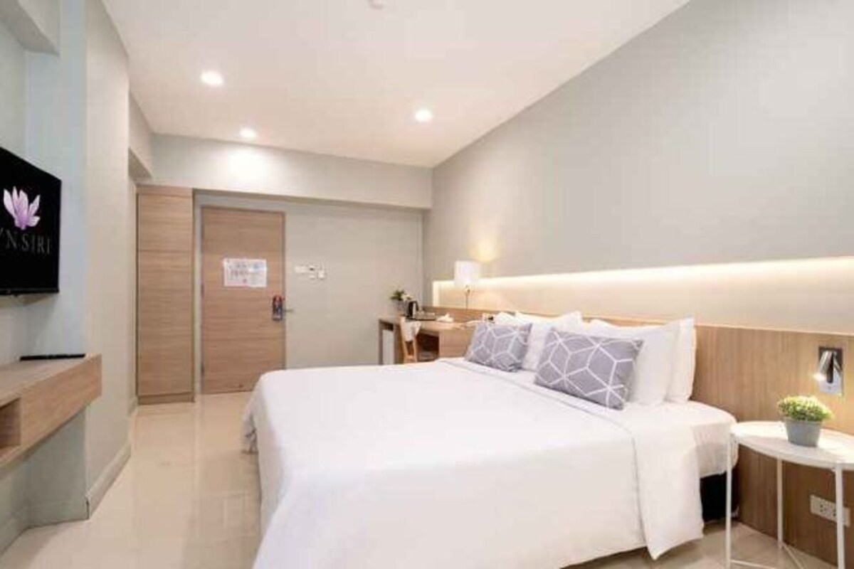 Une chambre d’hôtel moderne équipée d’un lit, d’une table de chevet, d’une lampe et d’un téléviseur fixé au mur.