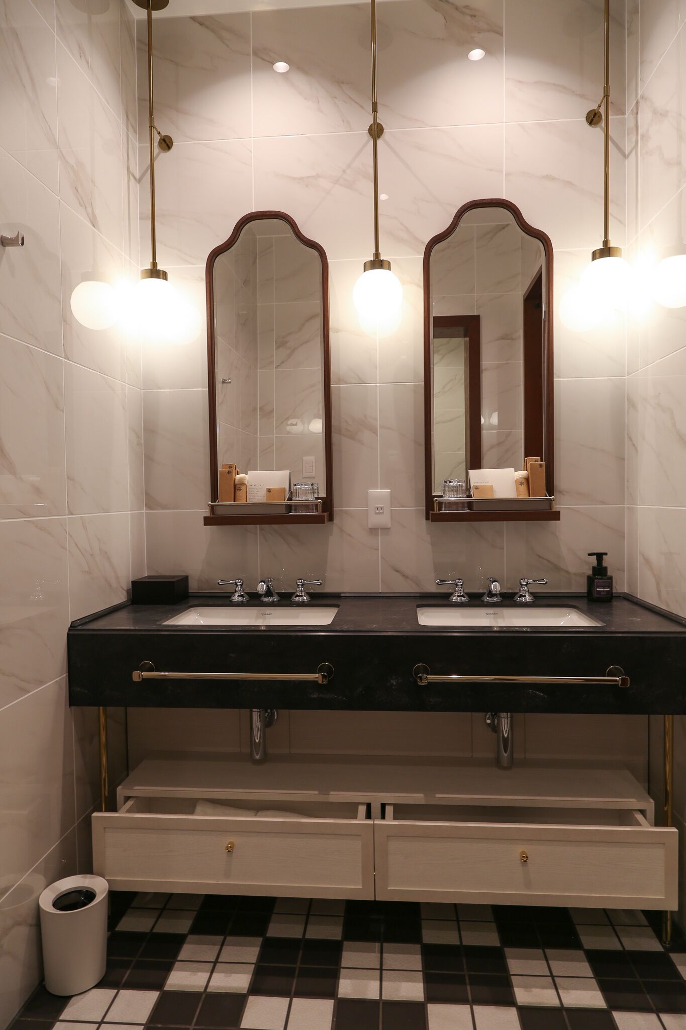 A bathroom with two sinks, a mirror, and a black and white checkered floor.