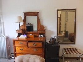 A wooden dresser with drawers, a mirror, a lamp, and a kettle.