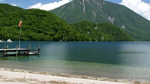 Un lago con un muelle y una bandera, rodeado de colinas verdes y exuberantes.