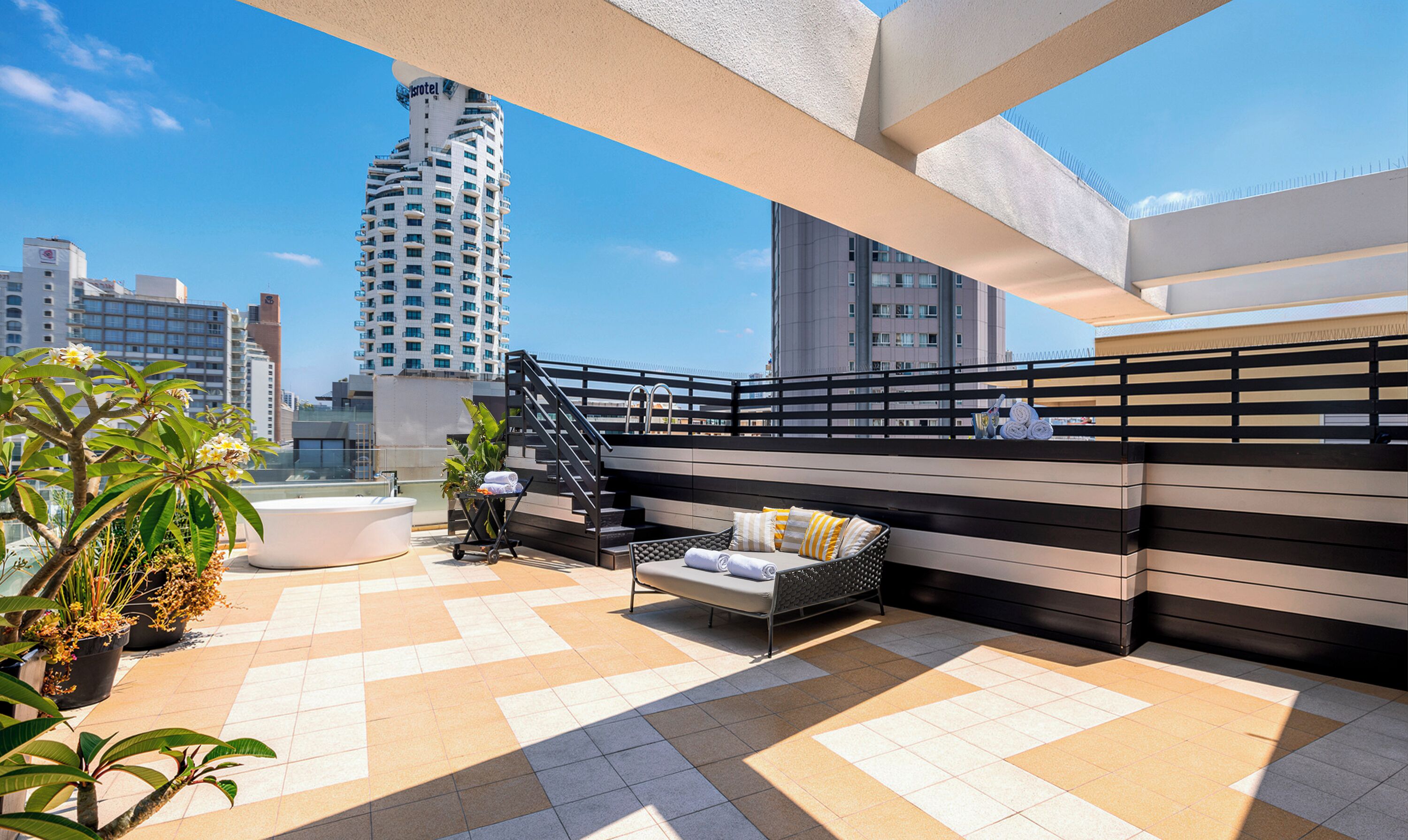A rooftop terrace with a seating area, a staircase, and potted plants.
