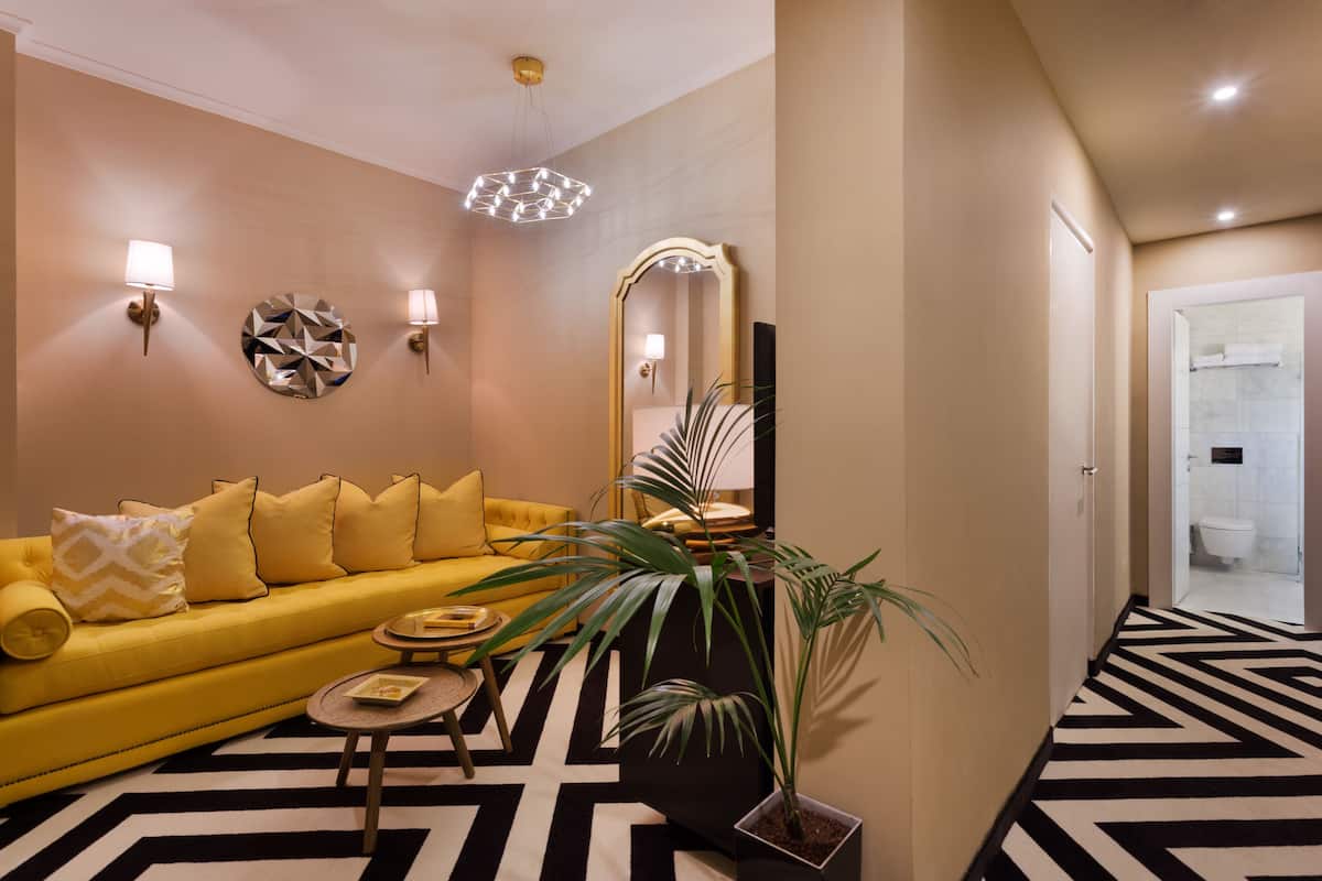 Un salon moderne avec un canapé jaune, une table basse ronde et un grand miroir.