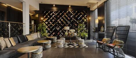 A modern lounge area with a dark patterned wall, a sofa, ottomans, and a seating area with chairs.