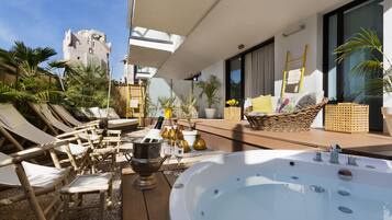 Une terrasse sur le toit, dotée de chaises longues, d’un jacuzzi et de plantes en pot.