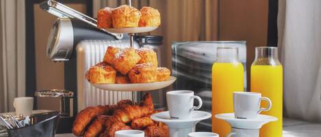 A breakfast setup with pastries, coffee cups, and orange juice bottles.