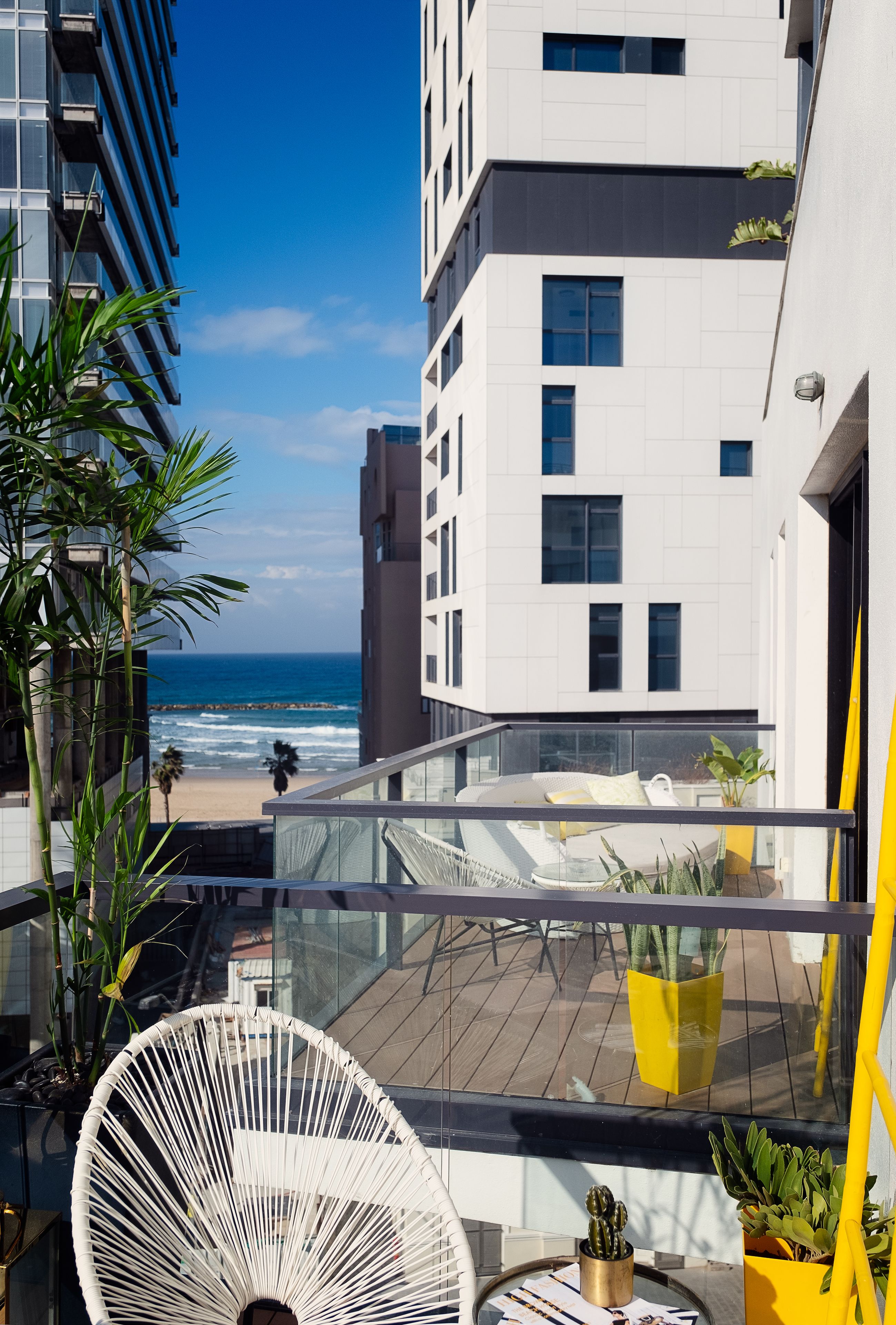 A modern building with a balcony overlooking a beach.