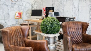 A room with two brown leather armchairs, a round table with a green topiary centerpiece, and a computer desk in the background. - Chao She Hotel (Kaohsiung)