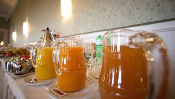 A buffet table with various food items and a pitcher of orange juice.