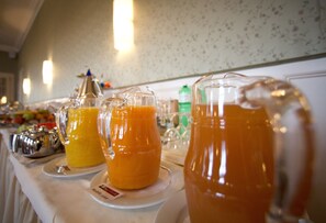 Una mesa de buffet con diferentes tipos de comida y una jarra de jugo de naranja.