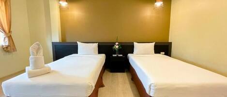 Une chambre d’hôtel avec deux lits simples, une table de chevet et une lampe fixée au mur.