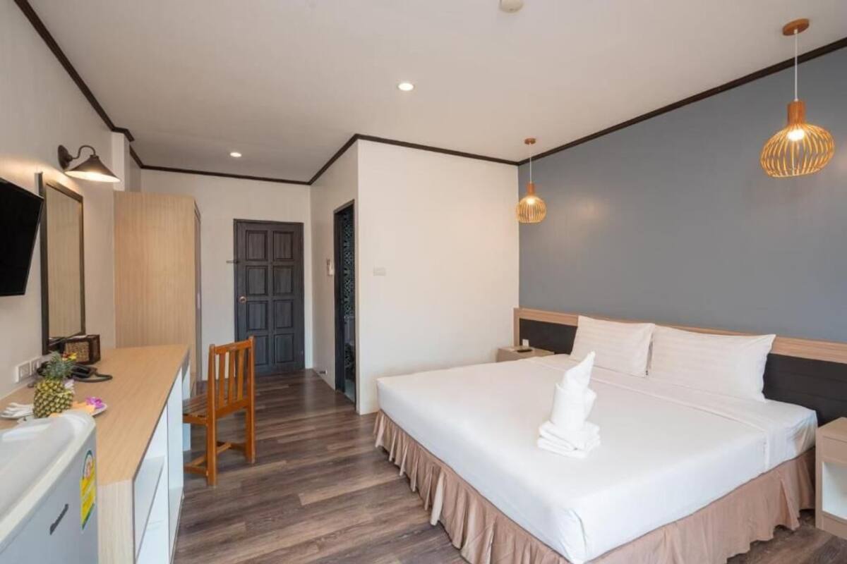A hotel room with a bed, a desk, a chair, and a television.