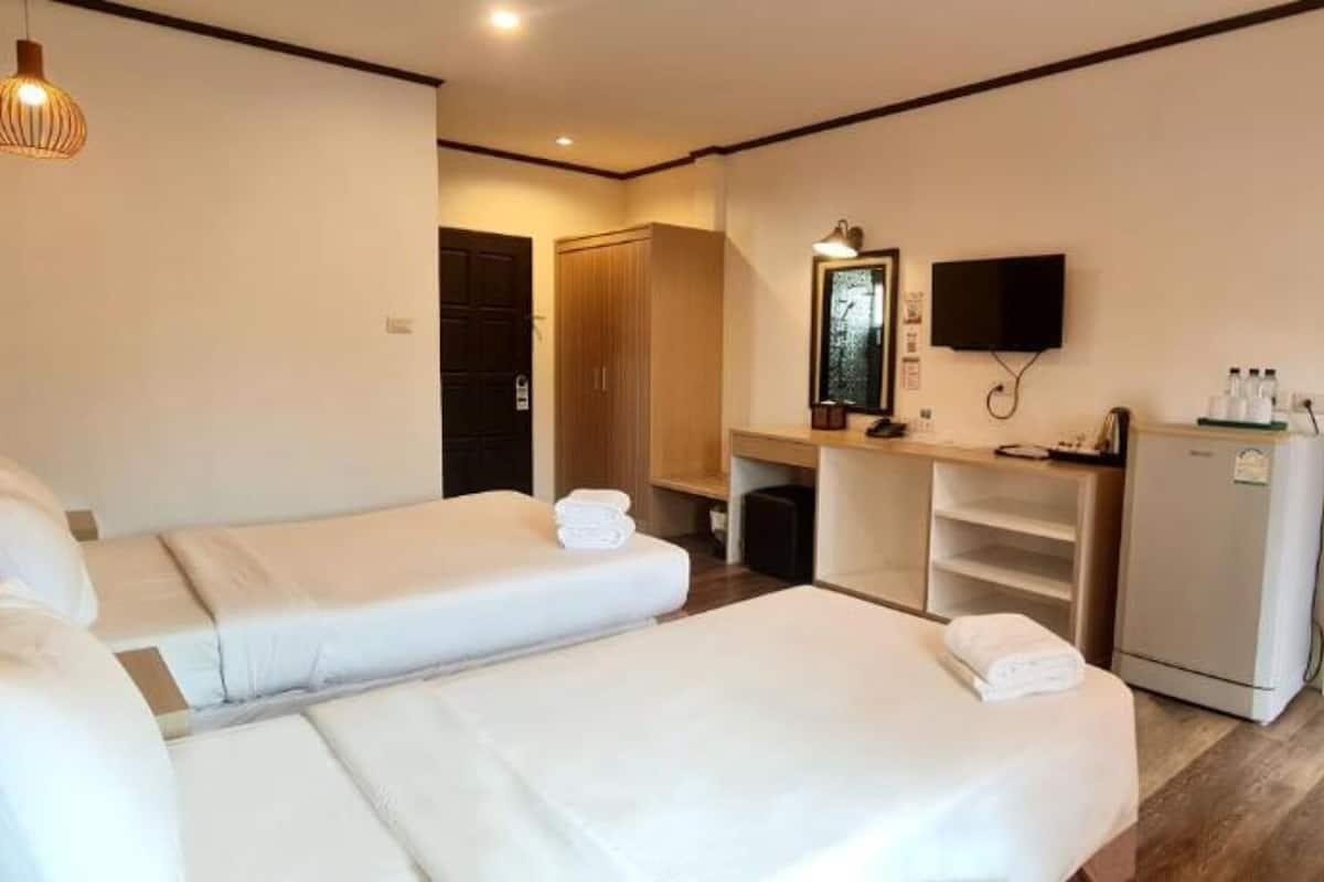 A hotel room with two single beds, a desk with a chair, a television, and a minibar.