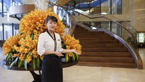 A person holding a large floral arrangement in a modern building with a staircase in the background. - Muong Thanh Luxury Nha Trang Hotel (Nha Trang)