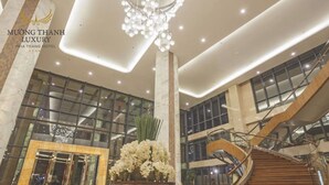 A spacious lobby with a grand staircase, marble columns, and a chandelier.