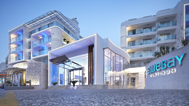 Een modern hotel met een glazen gevel, een opvallende ingang en een bord met de tekst 'BlueBay Platinum'.