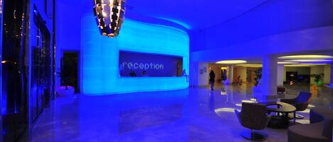 A modern lobby with a reception desk labeled "reception" and a seating area with contemporary chairs and tables.