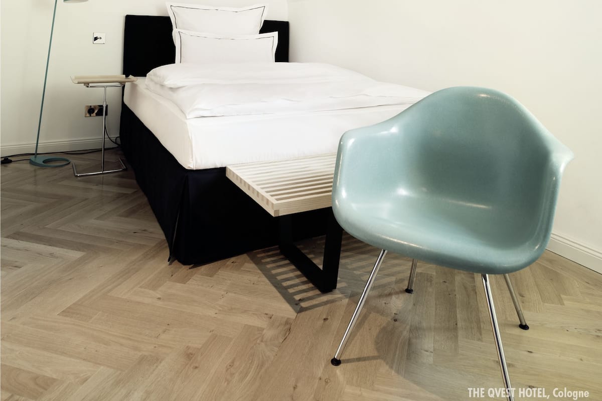 Ein Schlafzimmer mit einem Bett, einem Sessel, einer Stehlampe und einem Nachttisch.