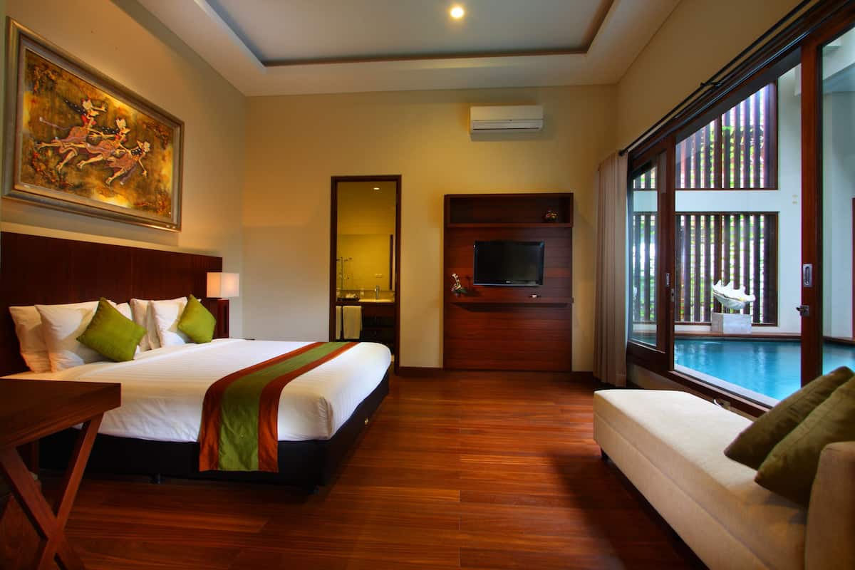 Habitación de hotel con una cama grande, un sofá, un televisor y vista a una piscina.
