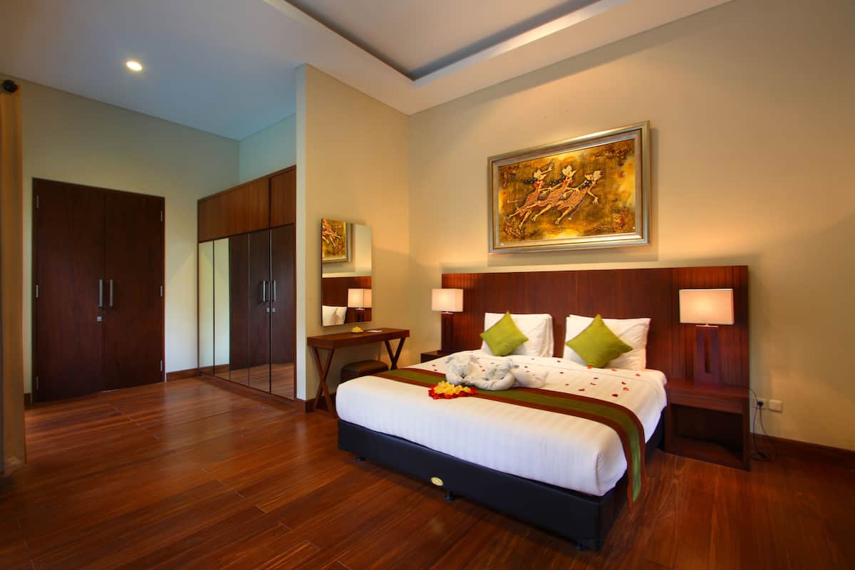 Un dormitorio amplio con una cama grande, un armario de madera y un cuadro sobre la cama.