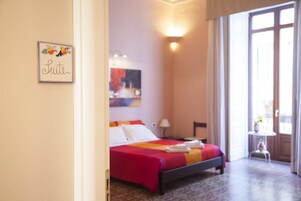 Una habitación de hotel con cama, mesita de noche, lámpara y un cuadro en la pared.