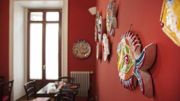 Un coin repas avec un mur rouge, une grande fenêtre et plusieurs chaises.