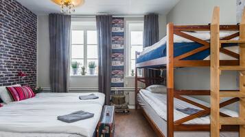 Una habitación con una litera, una maleta y una pared de ladrillo.