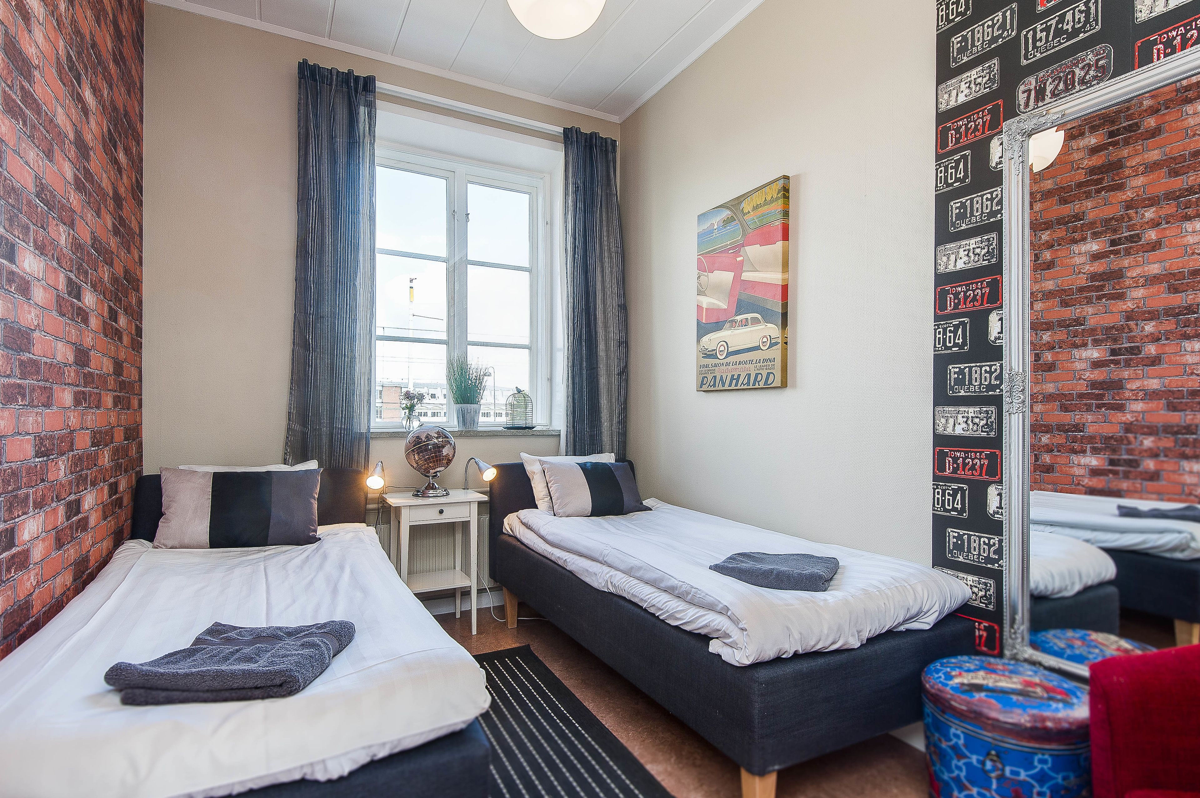 Een kamer met twee bedden, een bureau en een raam met gordijnen.