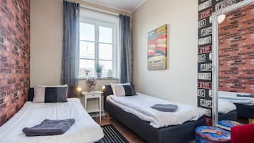 Een kamer met twee bedden, een bureau en een raam met gordijnen.