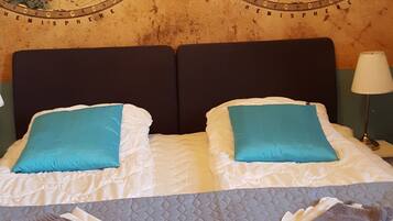 Habitación de hotel con un gran mapa del mundo en la pared, una cama con dos almohadas y una colcha acolchada.