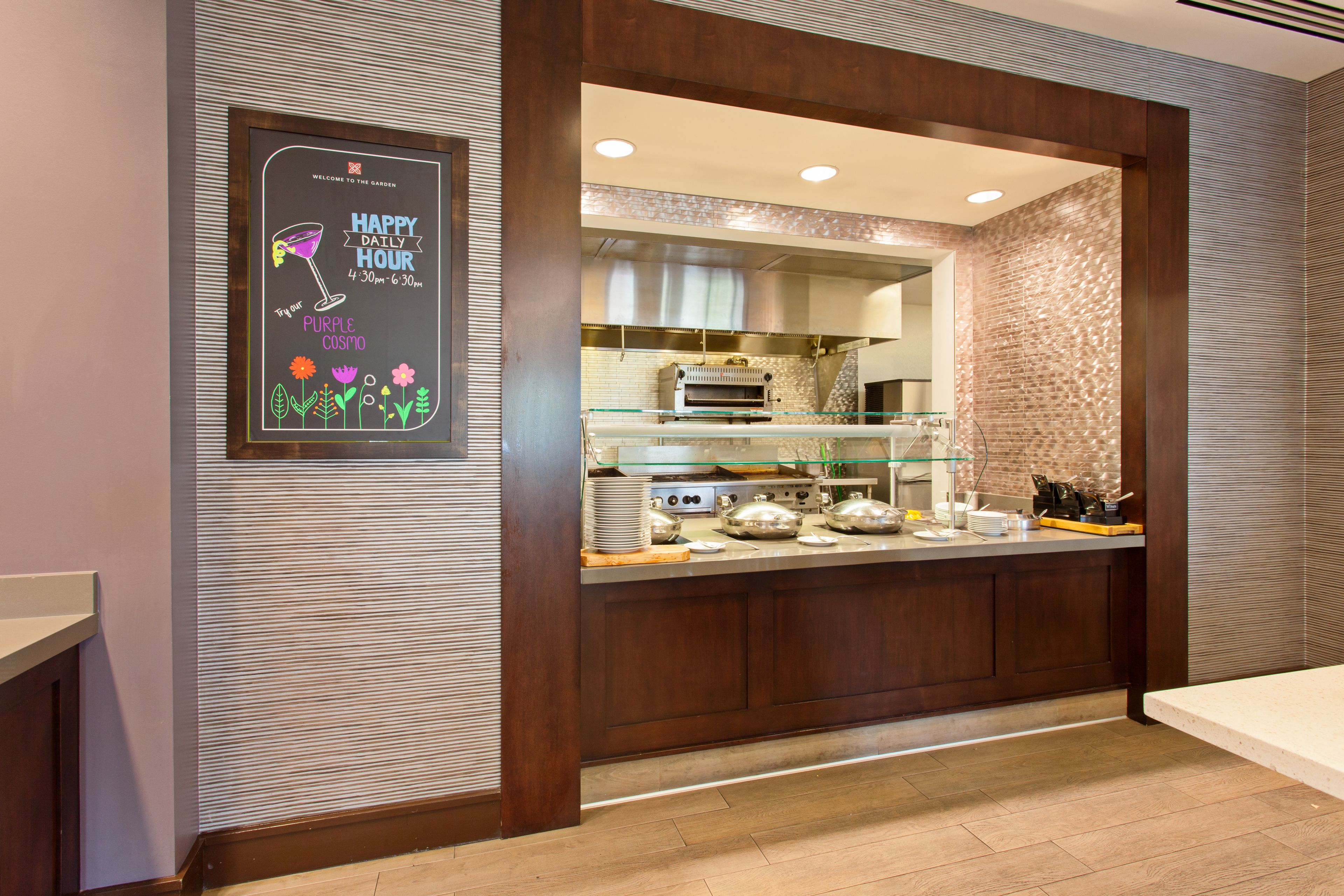 A breakfast bar with a glass enclosure, a framed poster, and a kitchen area with a brick backsplash.