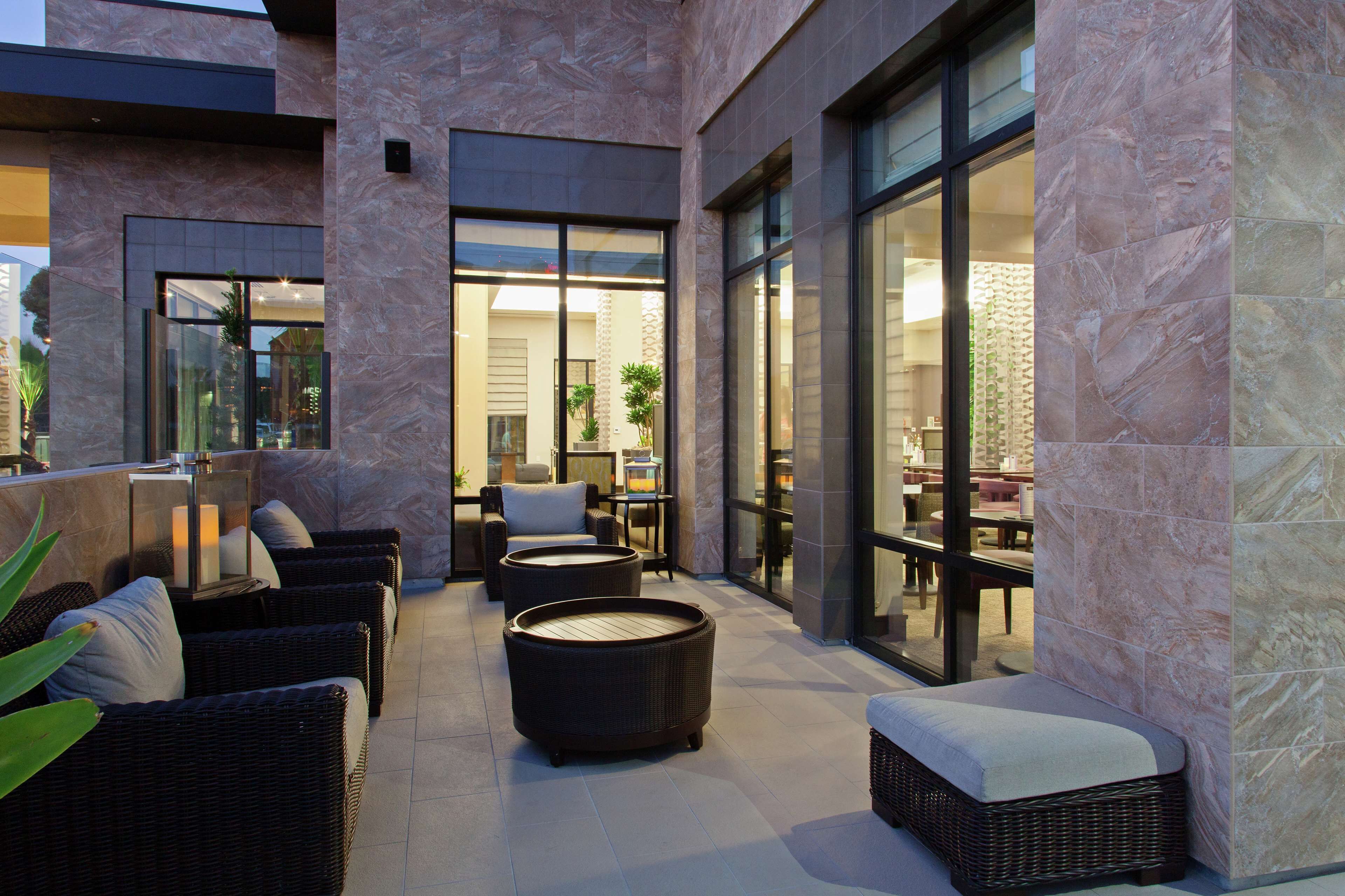 A modern outdoor seating area with wicker furniture and a stone wall.