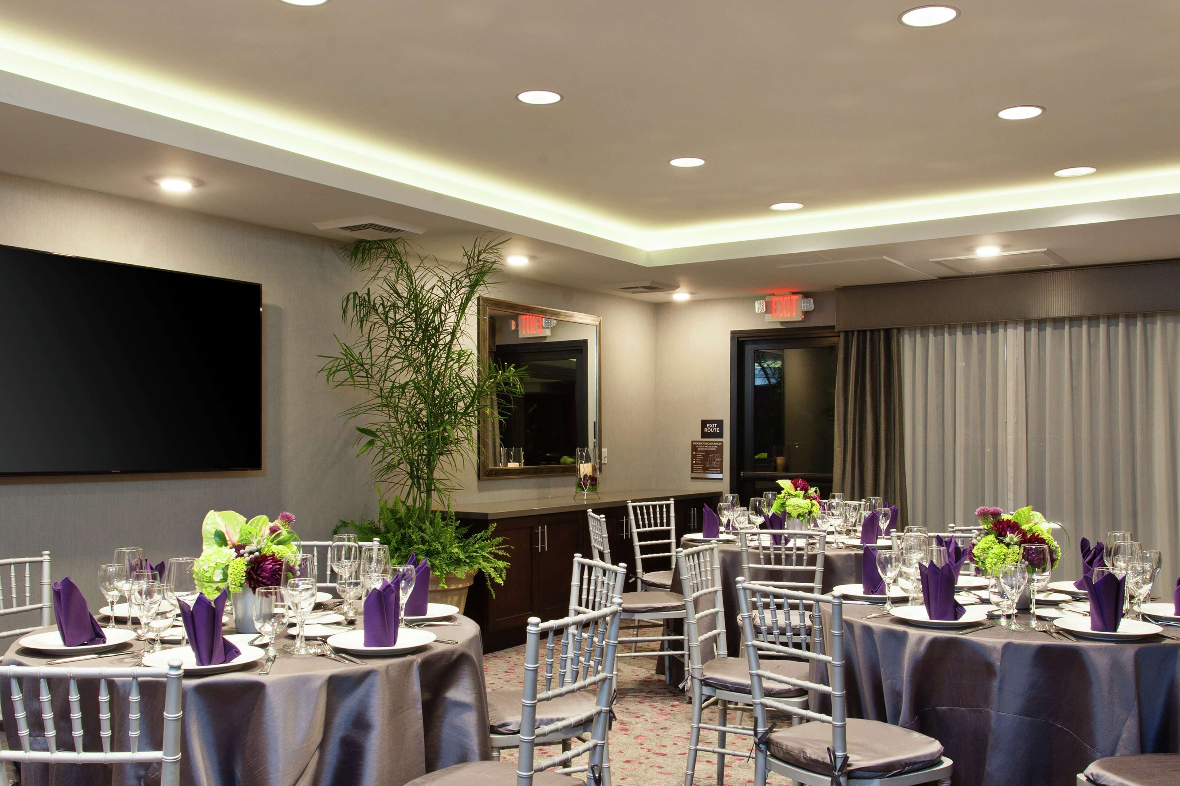 A conference room with round tables, chairs, and a large screen.