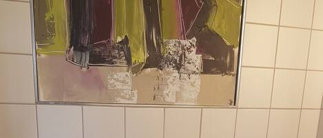 Un baño pequeño y funcional con inodoro, secamanos y cubo de basura.