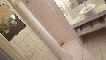 A bathroom with white tiles, a shower curtain, a sink, and a toilet.