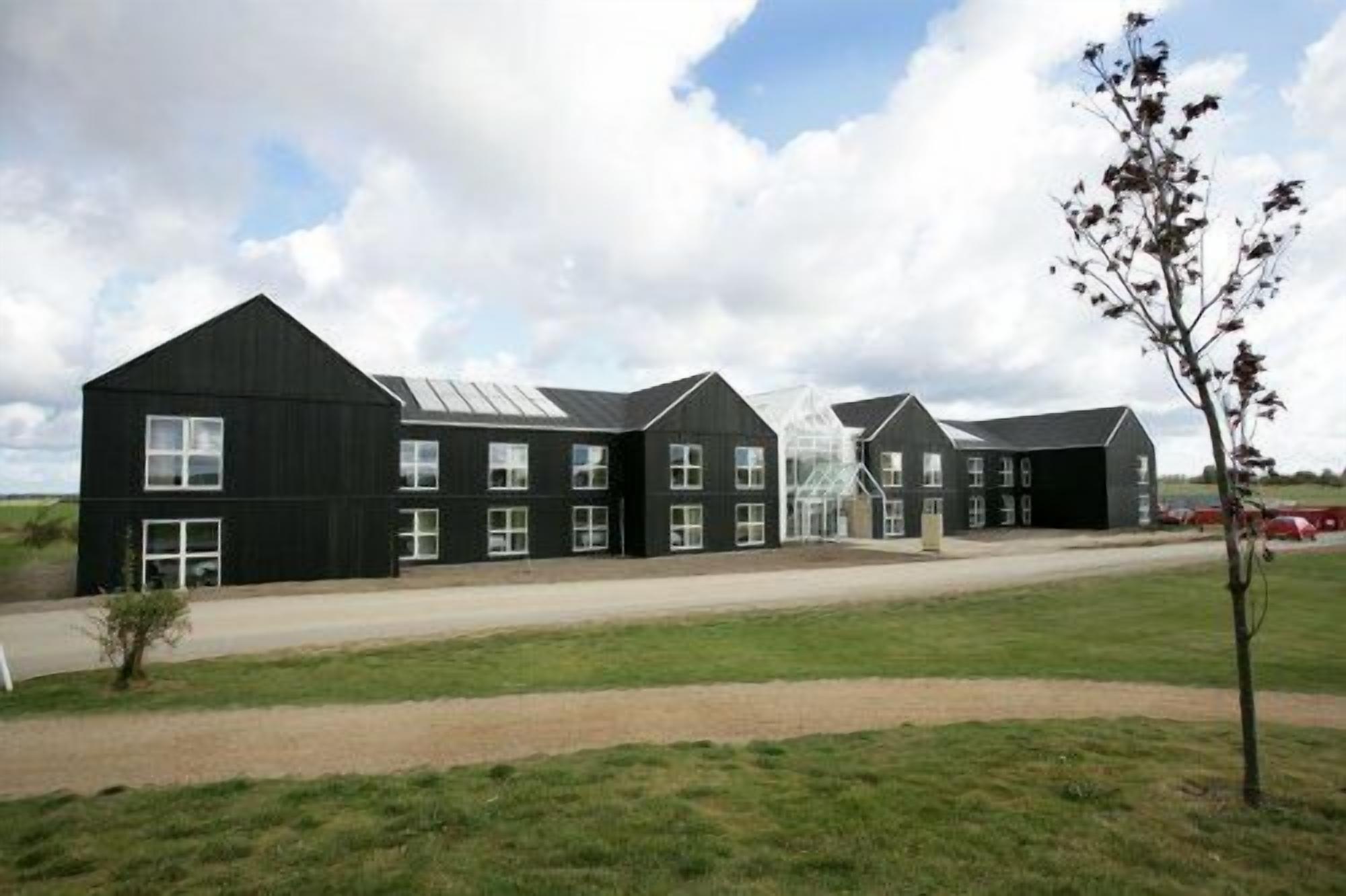 A row of black buildings with multiple windows and a central glass structure.