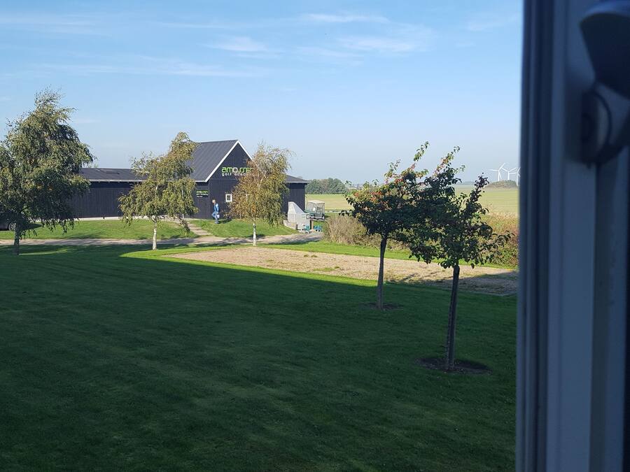 A view of a grassy area with a building in the background, a parked van, and a few trees.