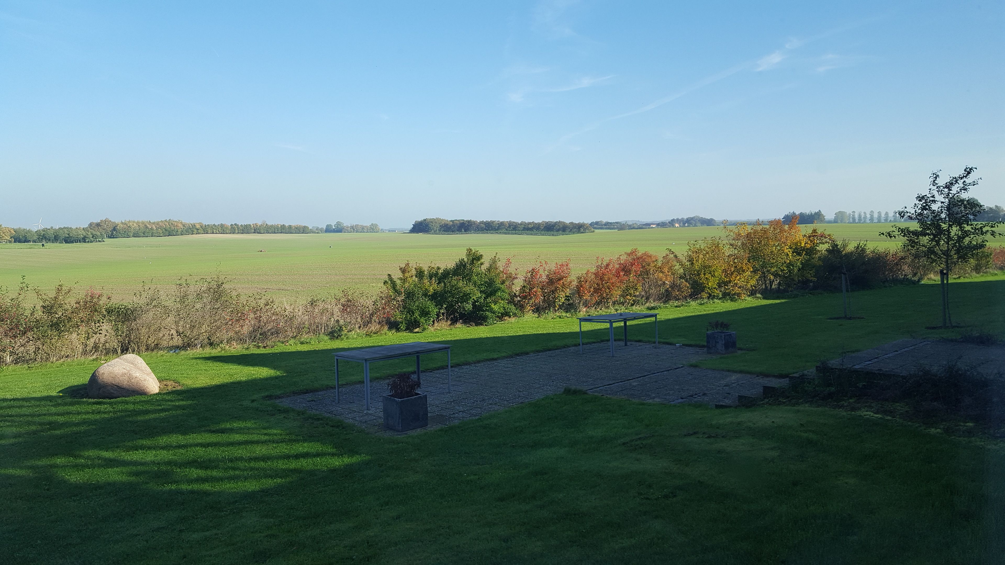 A grassy field with a bench and a stone structure.