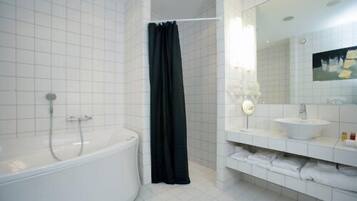 Une salle de bain moderne avec une baignoire blanche, un rideau de douche noir et un lavabo blanc avec un miroir au-dessus.