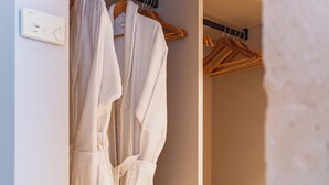A closet with white robes hanging on wooden hangers and shelves. - Canyamel Sun Suites Hotel (Capdepera)