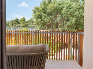 Un balcon donnant sur des arbres et bordé d’une clôture.