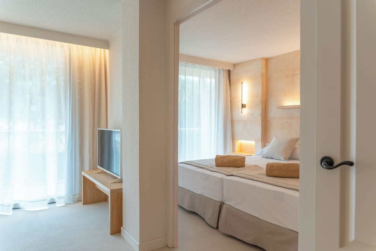 Habitación de hotel con cama, mesita de noche, televisor y vistas al exterior.