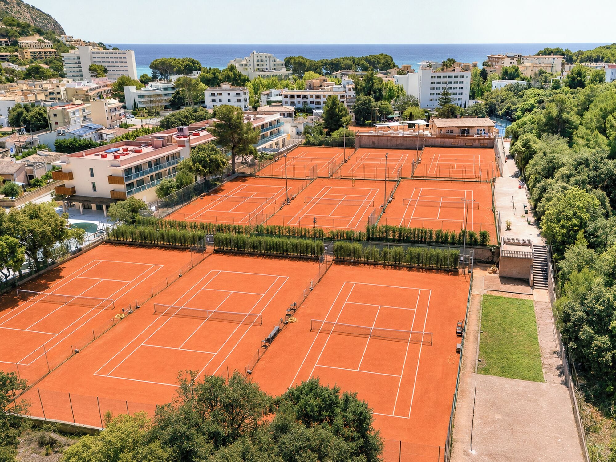 Un complesso di campi da tennis con più campi, circondato da edifici e aree verdi.