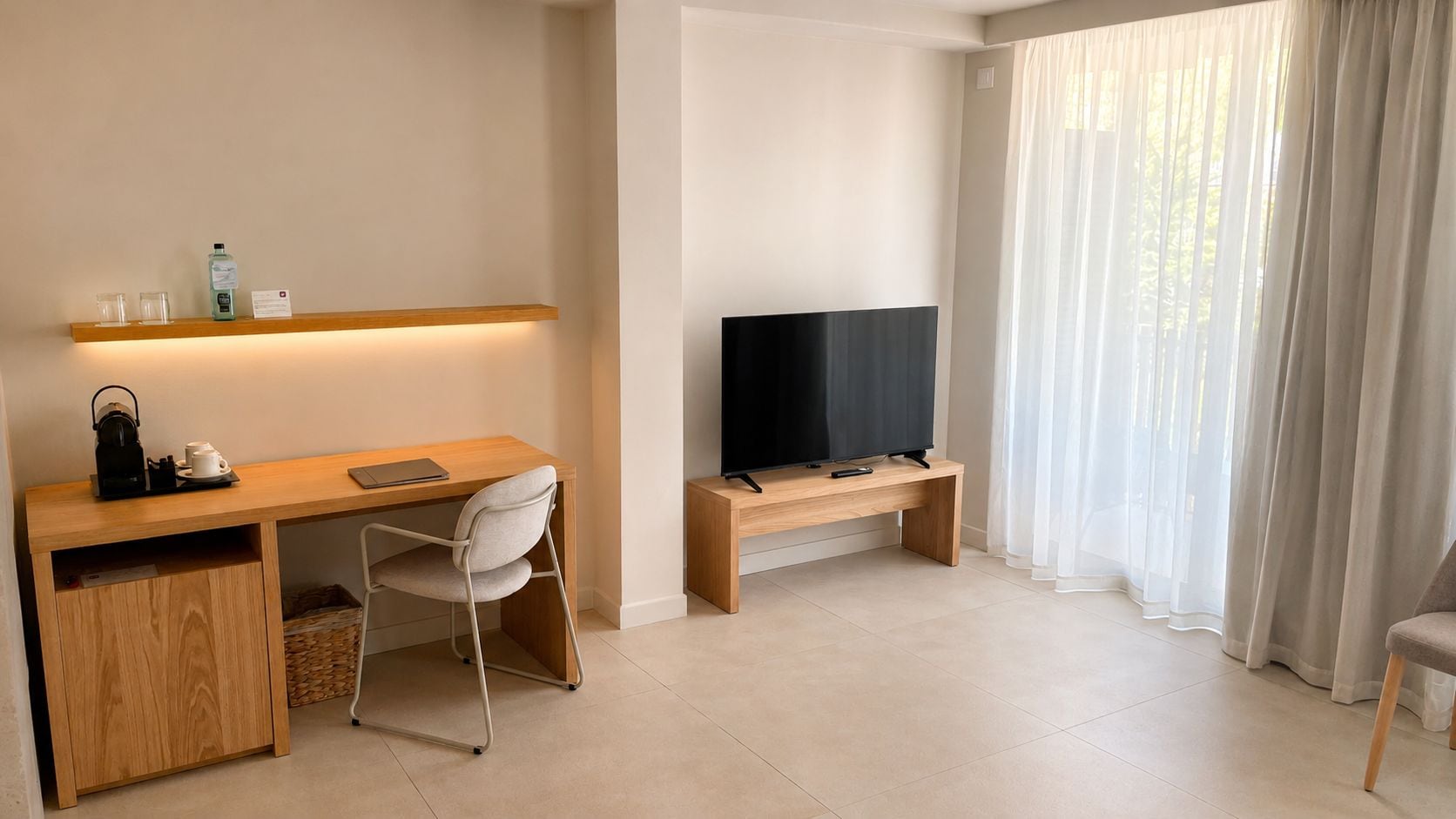 A modern living room with a wooden desk, a television on a stand, a white chair, and a large window with sheer curtains.