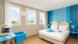 Un dormitorio con cama, escritorio, silla y vistas al exterior.